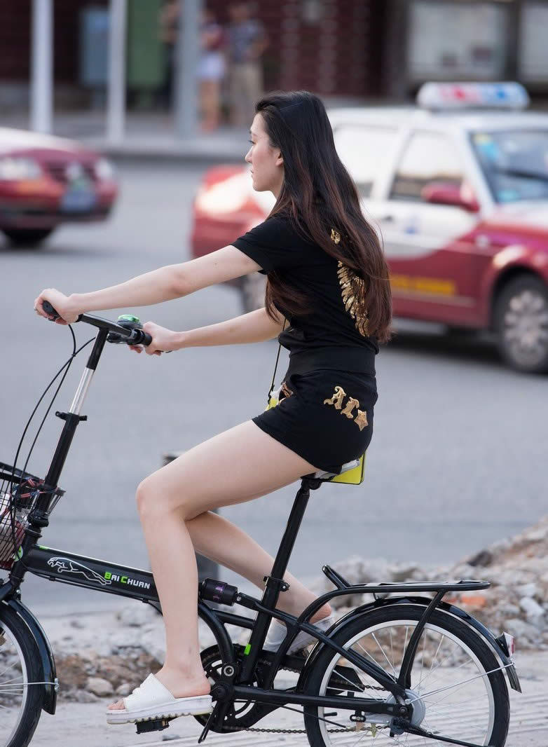 上班途中骑单车的长发美女黑色短裤美腿引诱图片